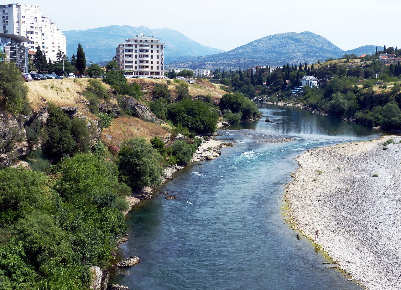 Morača river flowing thorugh Podgorica with buildings in the background.