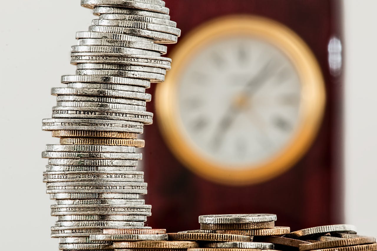 Stack of coins with a clock in the background