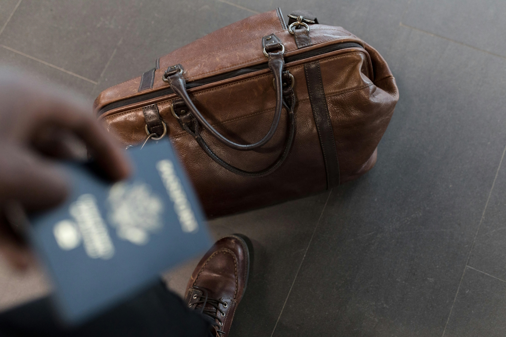 Person holding a passport with a bag on the floor